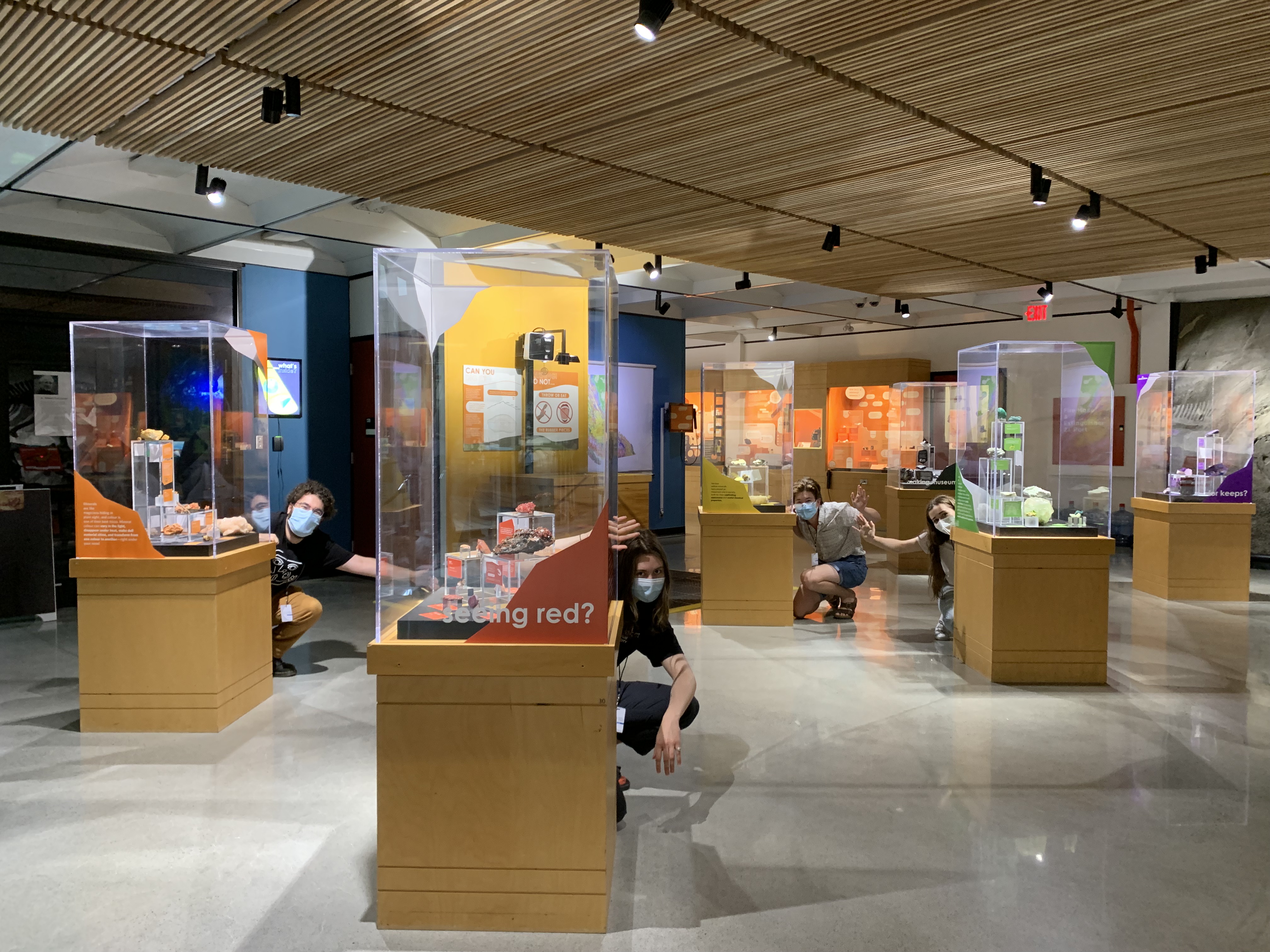 Photo of main gallery of the Pacific Museum of Earth with students crouching down behind some of the displays.